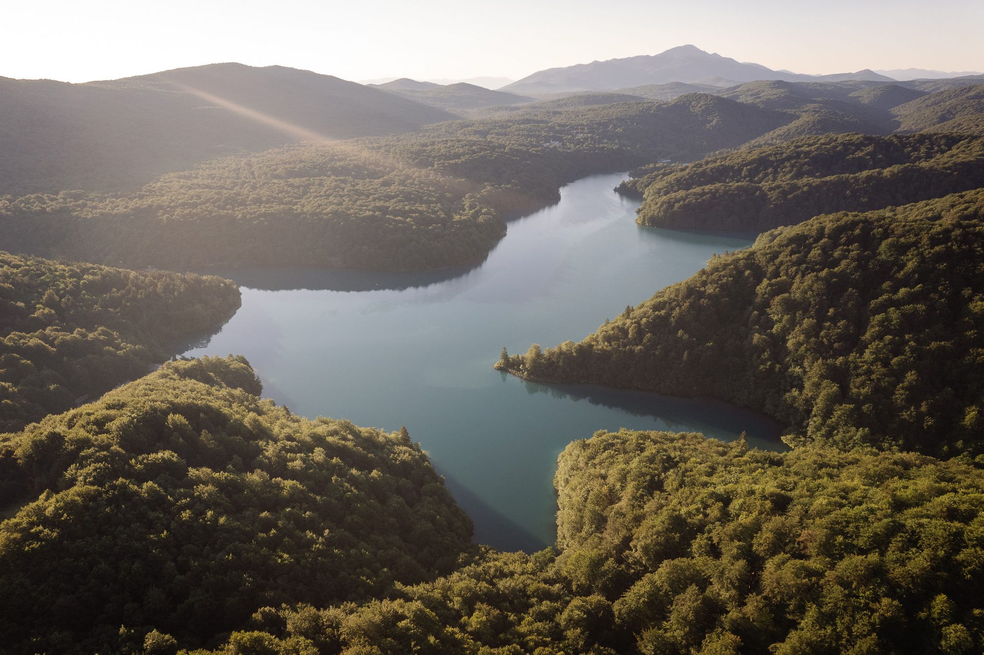 Aerial view of a turquoise lake winding through the forested hills of Plitvice Lakes National Park