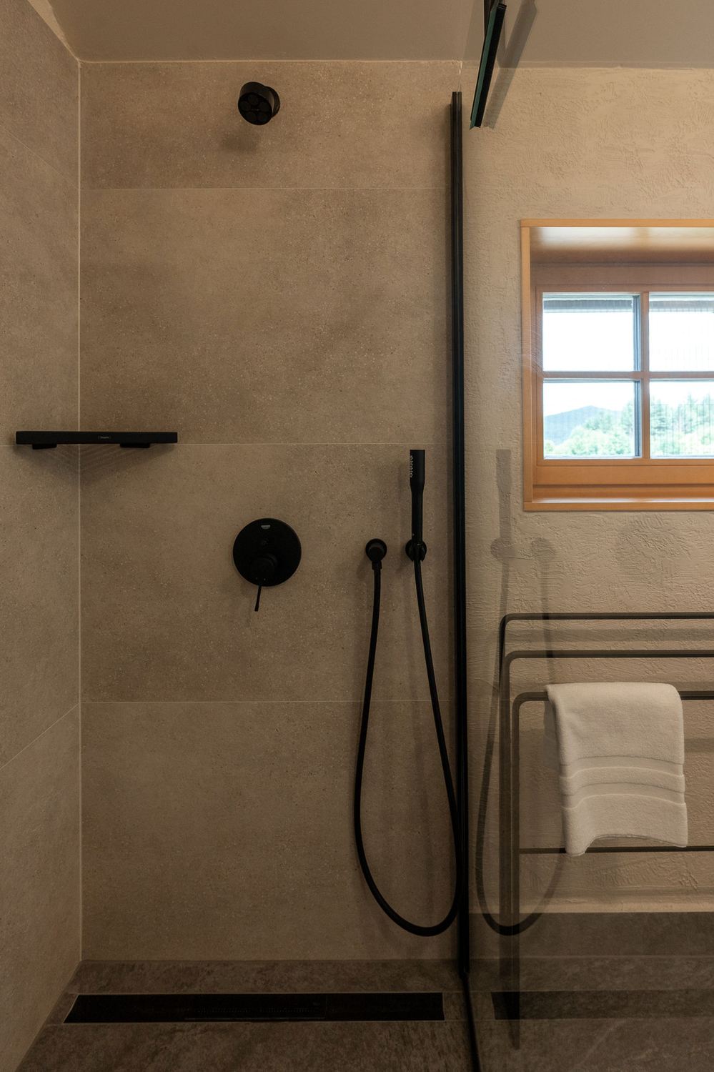 Bathroom shower with dark fixtures and natural stone tile