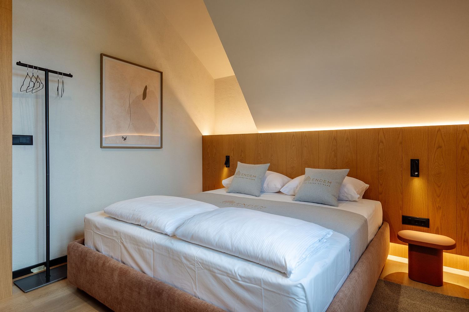 Bedroom with warm wood headboard, soft bedding and a window looking out to the forest