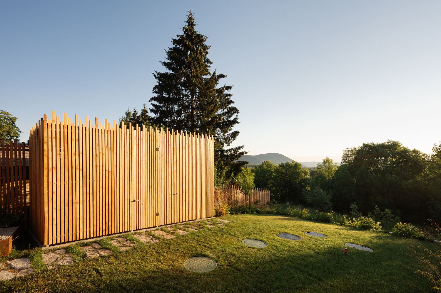 Timber slat fence beside a fir tree in the garden