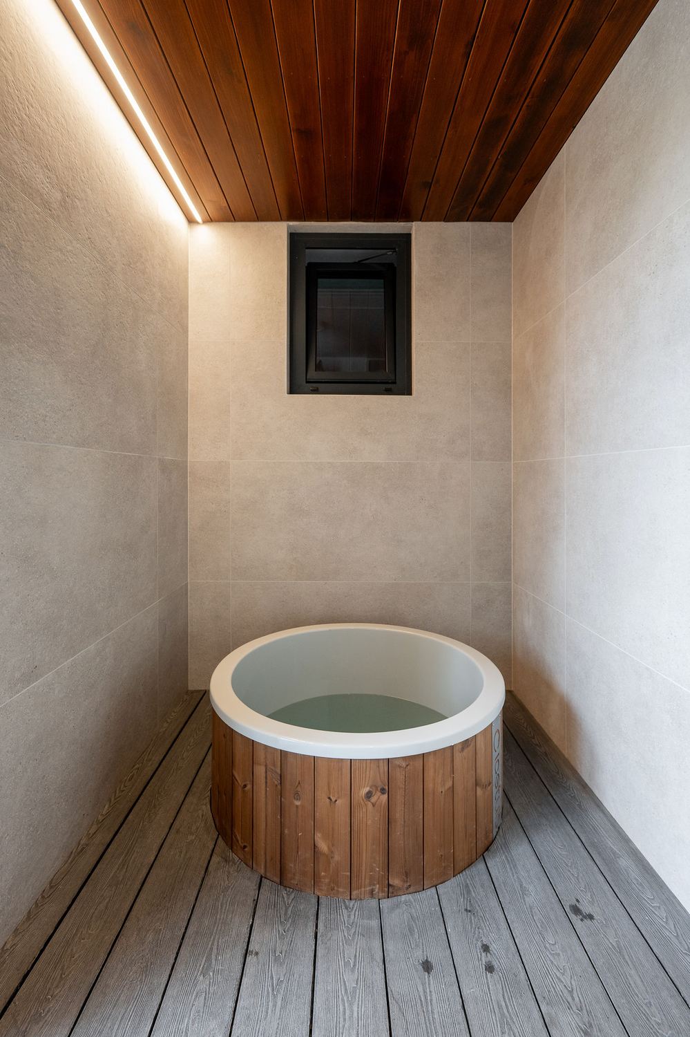 Wood-fired ice tub in a stone and timber wellness room
