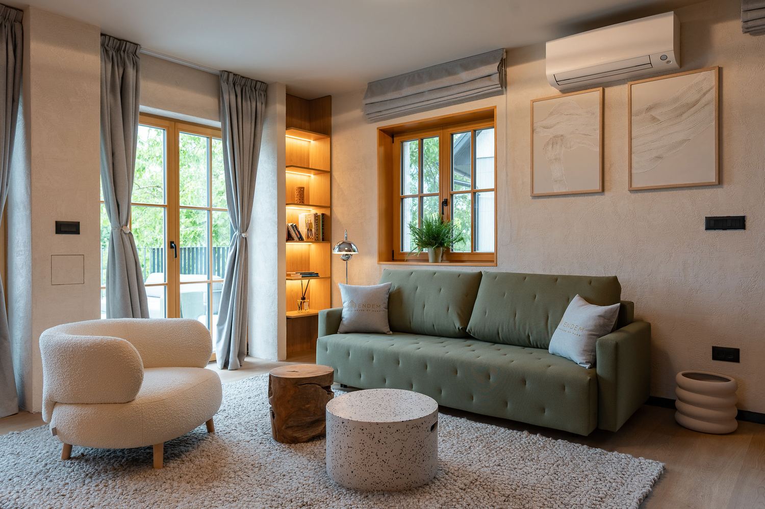 Open-plan living room with a green velvet sofa, cream armchair and warm wood accents