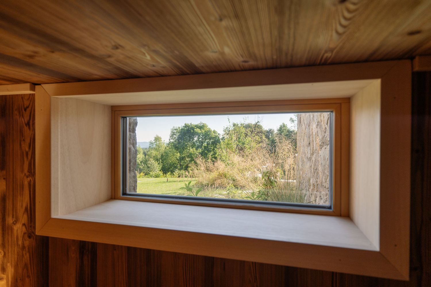 View through a timber-framed window of the surrounding forest and meadow